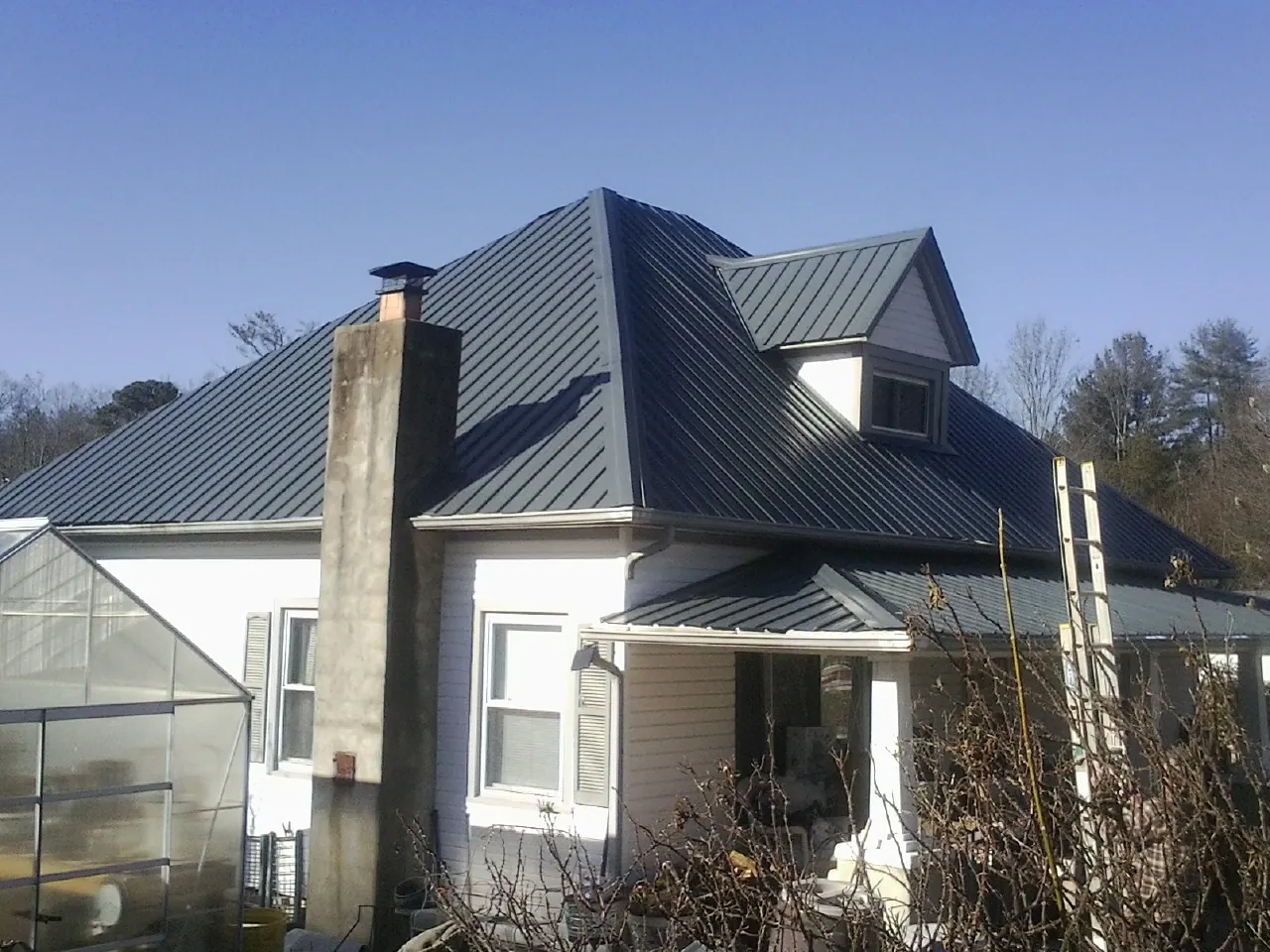 Dark blue standing seam metal roof on a white farmhouse with dormer — Slate & Tile Roof Repair by Roofing Brothers in Brinkhaven