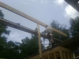 Carpenter setting a ridge beam over a new addition frame — Ice Dam Removal by Roofing Brothers in Brinkhaven