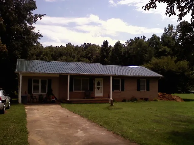 Dark green metal roof on a brick ranch with a covered porch in Brinkhaven