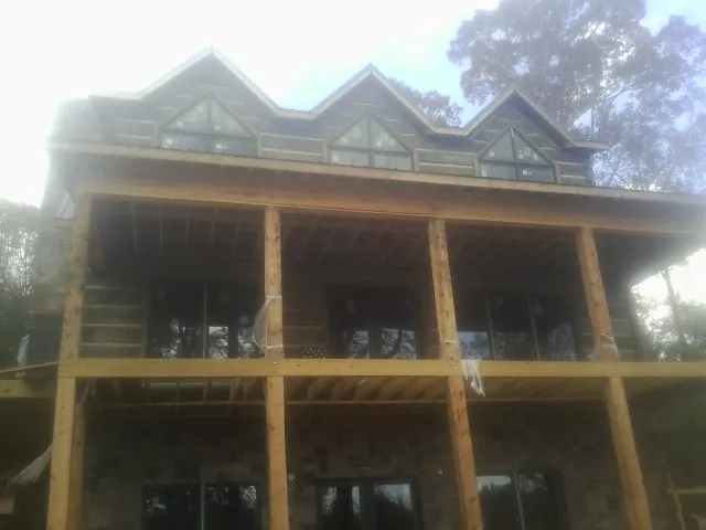 Dormers and porch framing on a large log home under construction — Roof Coating work by our crew in Brinkhaven