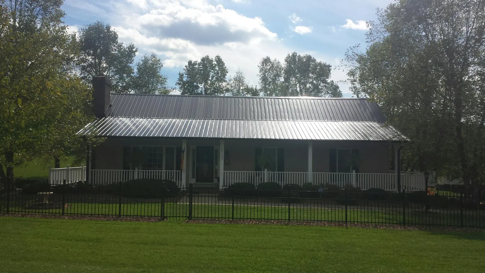 Gray metal roof on a brick ranch with a full width front porch — Gutter Guard Installation work by our crew in Brinkhaven