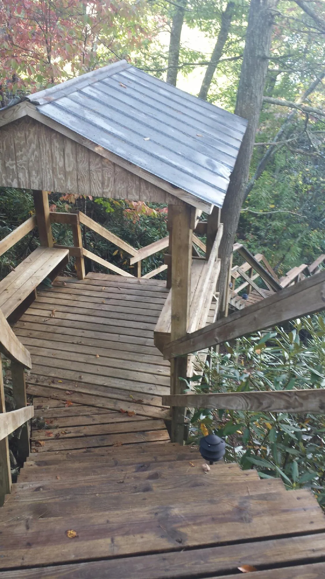 Metal roofed shelter over wooden steps on a wooded walkway — Skylight Repair & Installation work by our crew in Brinkhaven