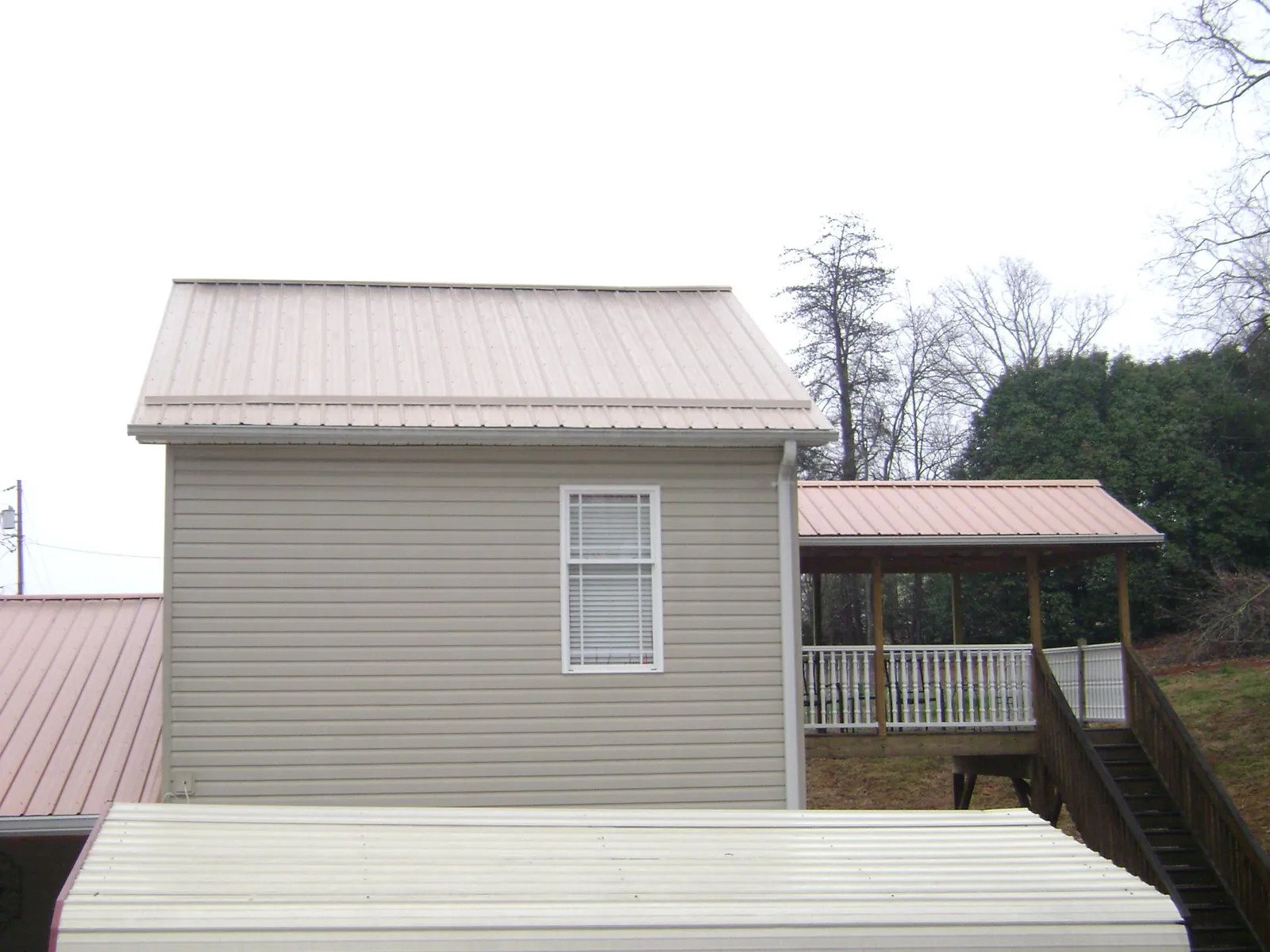Tan metal roofs on a two story addition and attached porch, from a Roof Replacement job in Brinkhaven