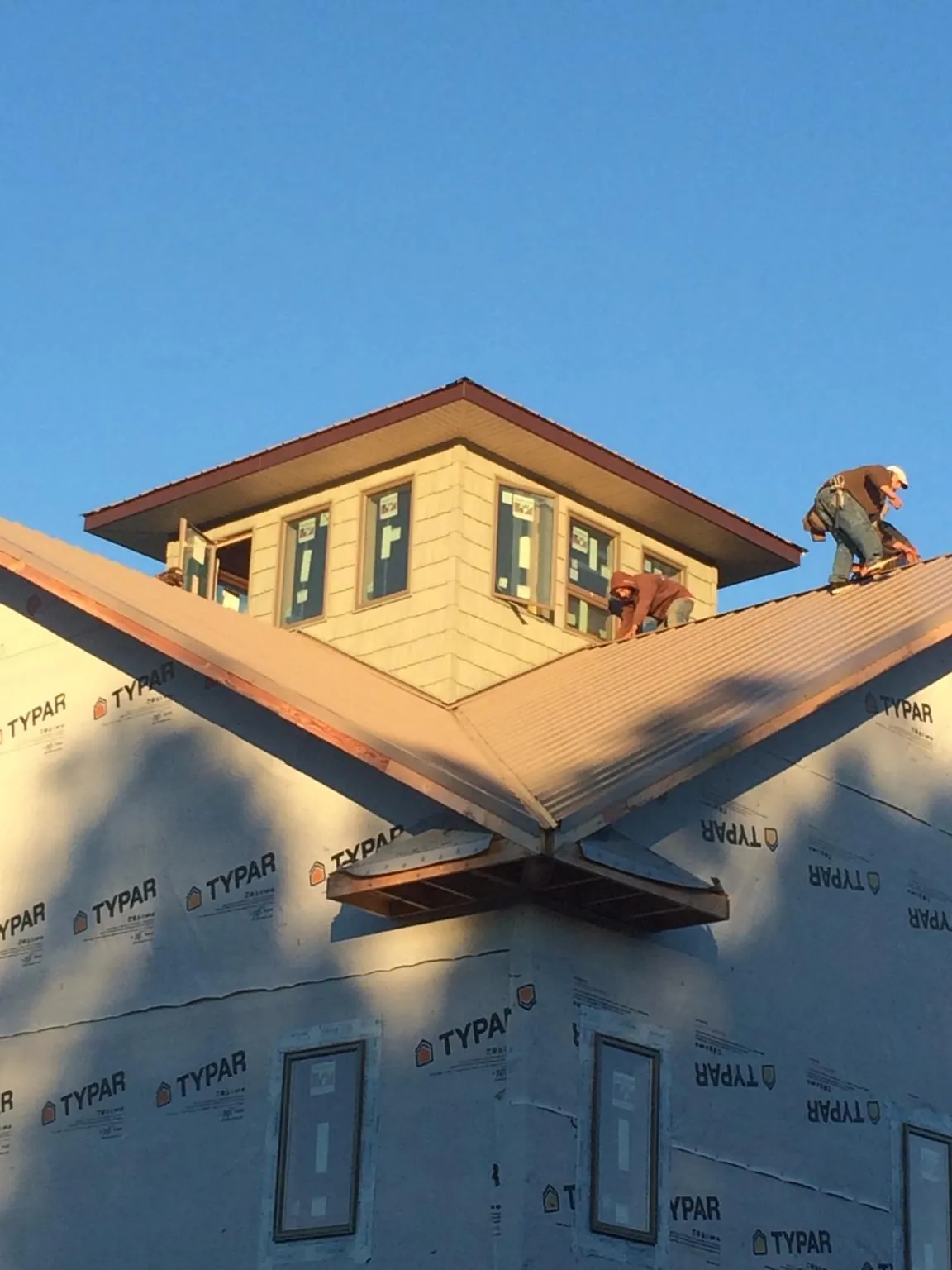 Roofers working around a rooftop cupola on a new metal roof at sunset — Roof Waterproofing in Brinkhaven by Roofing Brothers